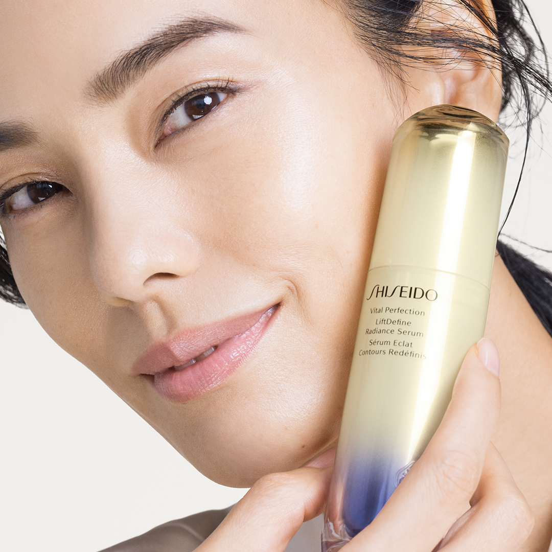 Woman holding up the Shiseido LiftDefine Radiance Serum bottle